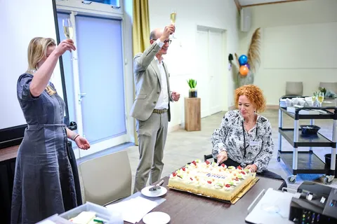 Collega's toosten met champagne terwijl een taart wordt aangesneden