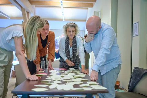 Deelnemers buigen zich over gele memoblaadjes verspreid op tafel tijdens een oefening