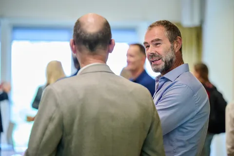 Man kijkt lachend over zijn schouder tijdens een gesprek
