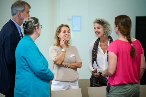 Groep deelnemers praat lachend met elkaar in een kring
