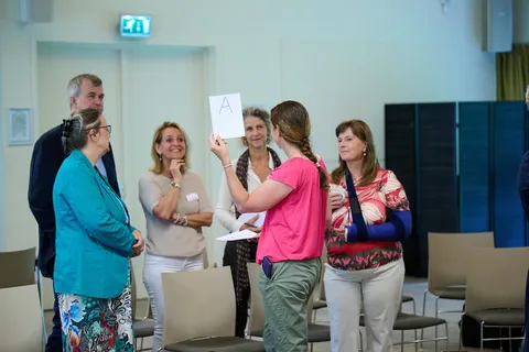 Deelnemer houdt een kaartje met de letter A omhoog tijdens de quiz
