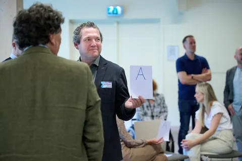 Man houdt een kaartje met de letter A omhoog tijdens een quizvraag