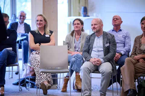 Publiek luistert glimlachend tijdens een presentatie
