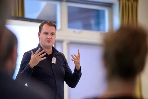 Man gebaart met beide handen tijdens een presentatie voor toehoorders