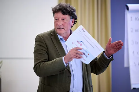 Man licht een brochure toe terwijl hij naar het scherm gebaart