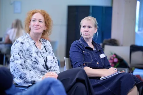 Twee vrouwen luisteren aandachtig tijdens een sessie