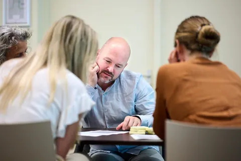 Man luistert aandachtig aan tafel tijdens een workshopgesprek