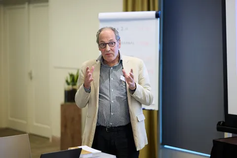 Man met bril spreekt gebarend voor een flipover